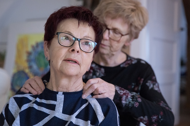 Zwei ältere Frauen: eine massiert die andere im Hals-Schulterbereich