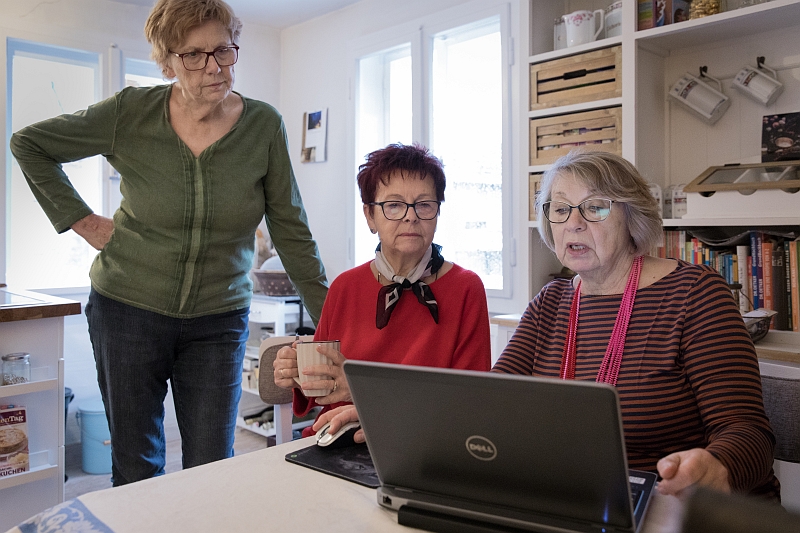Drei ältere Frauen bestellen gemeinsam am Laptop Tickets für eine Museumsbesuch