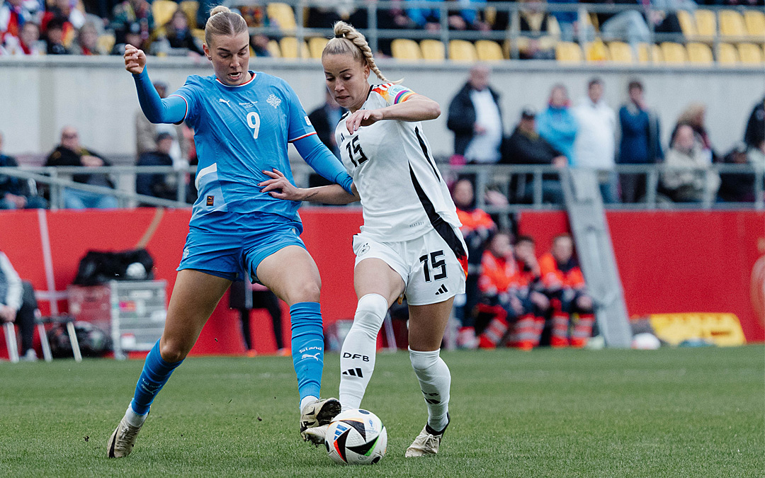 Zweikampf zwischen einer isländischen Fußballerin im blauen Trikot und einer deutschen im weißen Trikot.