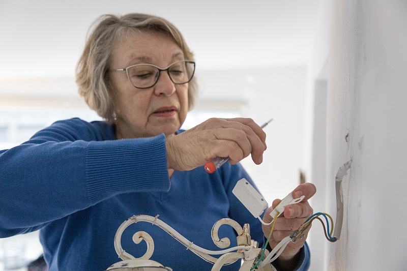 Alte Frau montiert eine Wandlampe