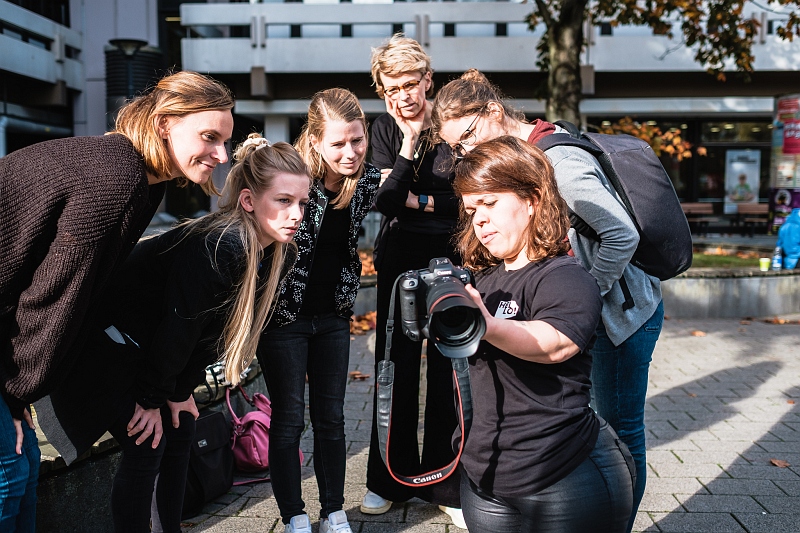 Eine Gruppe von fünf jungen Leuten schauen auf das Display der Fotografin Anna Spindelndreier bei einem Foto-Workshop