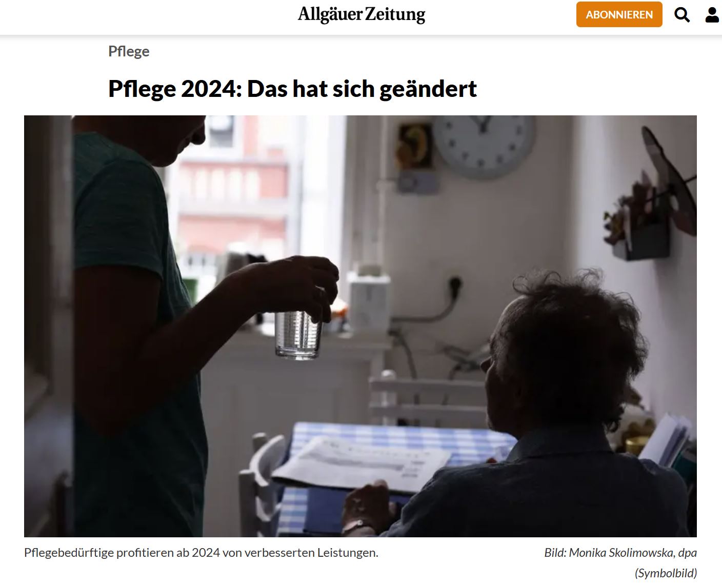 Screenshot Foto Gegenlicht: eine Helferin reicht einer alten Frau ein Glas Wasser in einer Küche